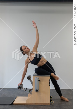 Caucasian woman doing Pilates on classic chair. 134784658