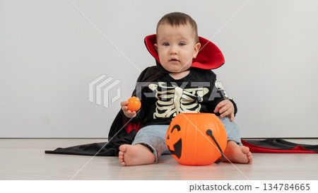 Cute caucasian boy in dracula halloween costume holding candy basket on white background. Cute caucasian boy in dracula halloween costume holding candy basket on white background. 134784665