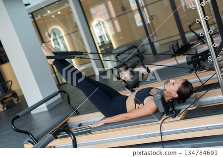 Caucasian woman doing exercises on reformer machine.  134784691