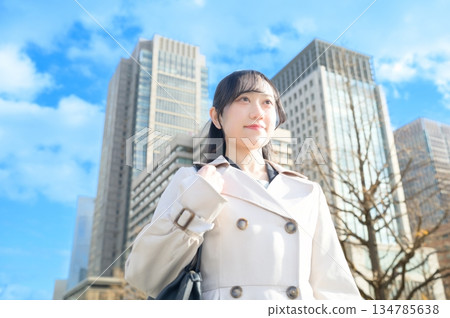 A woman looking up at the sky in an office district A woman looking up at the sky in an office district 134785638