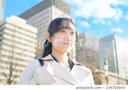 A woman looking up at the sky in an office district A woman looking up at the sky in an office district 134785643