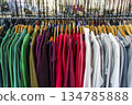 Colorful variety of vintage apparel and second-hand clothes hanging on a rack in a thrift shop or flea market. This image captures the concept of sustainable fashion, retro style, and the treasure 134785888