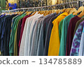 Colorful variety of vintage apparel and second-hand clothes hanging on a rack in a thrift shop or flea market. This image captures the concept of sustainable fashion, retro style, and the treasure 134785889