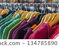 Colorful variety of vintage apparel and second-hand clothes hanging on a rack in a thrift shop or flea market. This image captures the concept of sustainable fashion, retro style, and the treasure 134785890