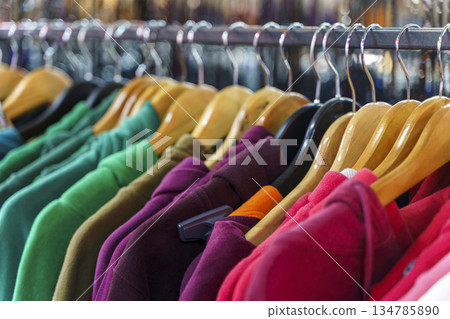 Colorful variety of vintage apparel and second-hand clothes hanging on a rack in a thrift shop or flea market. This image captures the concept of sustainable fashion, retro style, and the treasure 134785890