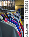 Colorful variety of vintage apparel and second-hand clothes hanging on a rack in a thrift shop or flea market. This image captures the concept of sustainable fashion, retro style, and the treasure 134785891