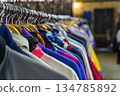 Colorful variety of vintage apparel and second-hand clothes hanging on a rack in a thrift shop or flea market. This image captures the concept of sustainable fashion, retro style, and the treasure 134785892
