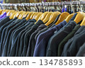 Colorful variety of vintage apparel and second-hand clothes hanging on a rack in a thrift shop or flea market. This image captures the concept of sustainable fashion, retro style, and the treasure 134785893
