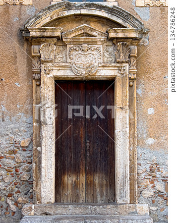 Carved stone archway framing old wooden door entrance 134786248