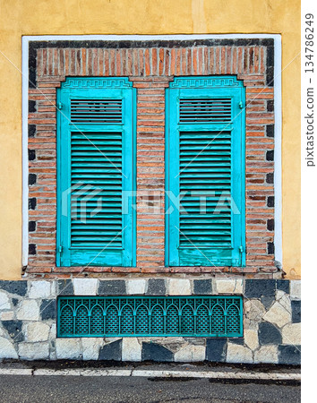 Building facade with turquoise shutters and patterned stonework Building facade with turquoise shutters and patterned stonework 134786249