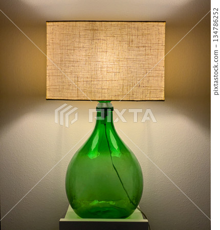 Upcycled green glass bottle lamp illuminating wall Upcycled green glass bottle lamp illuminating wall 134786252