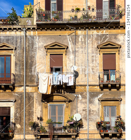 Weathered apartment building facade with laundry drying on balcony in italy Weathered apartment building facade with laundry drying on balcony in italy 134786254
