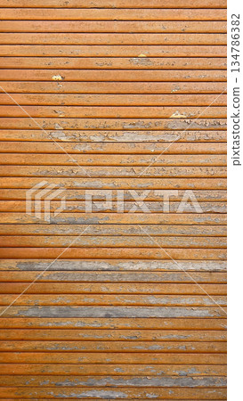 Weathered orange wooden slats showing peeling paint texture 134786382