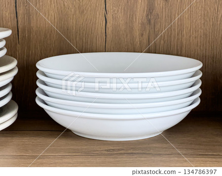 White ceramic bowls stacking on wooden kitchen shelf White ceramic bowls stacking on wooden kitchen shelf 134786397