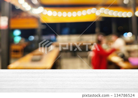 White wooden table top with blurred bbq restaurant background, Suitable for Product Presentation Backdrop, Display, and Mock up. 134786524