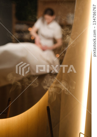 Relaxing massage in a quiet spa with soft lighting and soothing atmosphere and incense Relaxing massage in a quiet spa with soft lighting and soothing atmosphere and incense 134786767