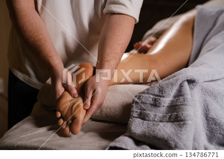 The master massages the feet of the foot. The expert foot massage technique, performed in a calm spa environment, is aimed at relaxing and relieving stress for the client. 134786771