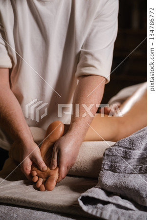 The expert foot massage technique performed by the master, performed in a calm spa environment, is aimed at relaxation and stress relief for the client The expert foot massage technique performed by the master, performed in a calm spa environment, is aimed at relaxation and stress relief for the client 134786772