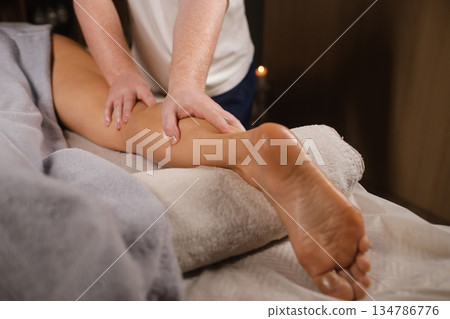 Relaxation session with a massage of women's feet in a cozy spa setting with soft lighting in the massage room 134786776