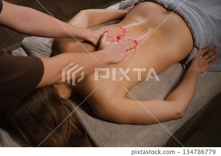 A massage therapist provides a relaxing back massage in a soothing spa setting. A massage therapist provides a relaxing back massage in a soothing spa setting. 134786779