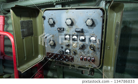 control panel inside armored turret showing dials, gauges, switches and aged wiring, olive paint surfaces, 134786833