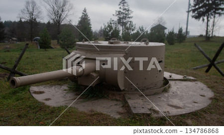 beige turret gun protrudes from circular bunker, short barrel aimed over landscape, concrete ring shows wear beige turret gun protrudes from circular bunker, short barrel aimed over landscape, concrete ring shows wear 134786868