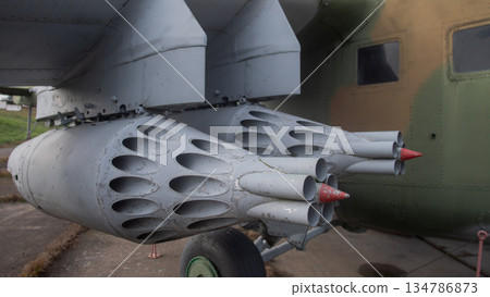 close-up rocket pod launcher with missiles and clustered tubes, weathered paint and red protective caps, 134786873