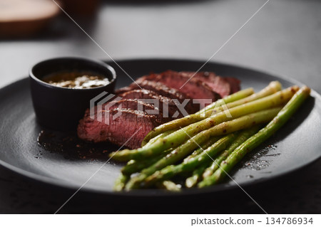 New york steak with asparagus on black plate with pesto sauce New york steak with asparagus on black plate with pesto sauce 134786934