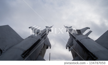 low-angle missile pair under cloudy sky, museum display emitting ominous cold war tension; metal surfaces, 134787050