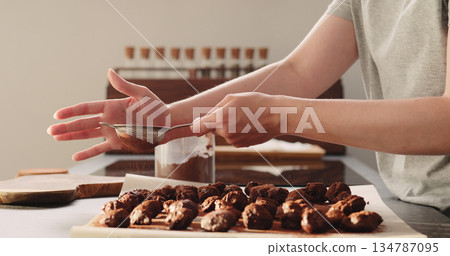 young woman sprinkle cocoa powder on chocolate truffles 134787095