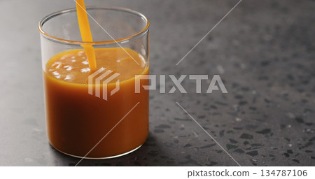 sea buckthorn juice pour into beaker glass on concrete surface 134787106