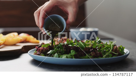 man making salad with nectarines and mozzarella on a blue plate on concrete countertop on kitchen, add dressing man making salad with nectarines and mozzarella on a blue plate on concrete countertop on kitchen, add dressing 134787117