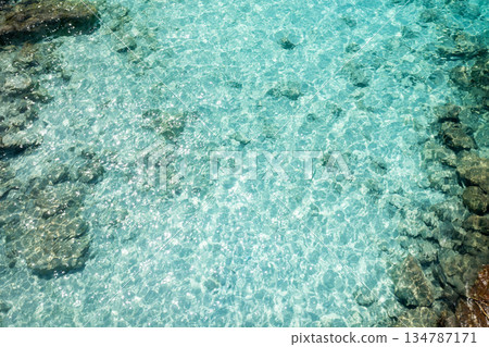 The clear turquoise water reflecting sunlight on a serene beach on a sunny day encourages relaxation and enjoyment of the beauty of nature The clear turquoise water reflecting sunlight on a serene beach on a sunny day encourages relaxation and enjoyment of the beauty of nature 134787171