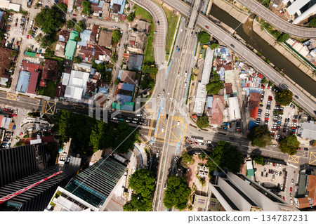 Top view of traffic moving through a busy intersection surrounded by buildings on a sunny city day. Kuala Lumpur. Malaysia Top view of traffic moving through a busy intersection surrounded by buildings on a sunny city day. Kuala Lumpur. Malaysia 134787231