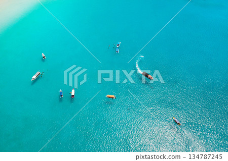 Tourist boats sailing on a sunny day on clear blue waters nearby. Tourists snorkeling near Redang Island 134787245