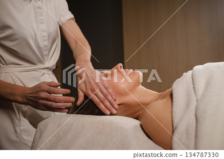 Relaxing massage treatment session at a spa location focusing on face and neck with a professional therapist during daytime Relaxing massage treatment session at a spa location focusing on face and neck with a professional therapist during daytime 134787330