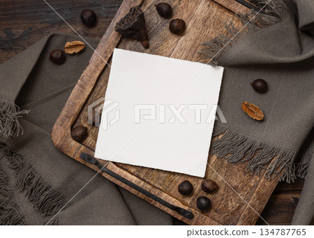 Square card on wooden tray near brown decor and grey linen cloth top view, boho mockup Square card on wooden tray near brown decor and grey linen cloth top view, boho mockup 134787765