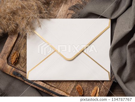 Envelope on wooden tray near brown decor and grey linen cloth top view, boho mockup 134787767