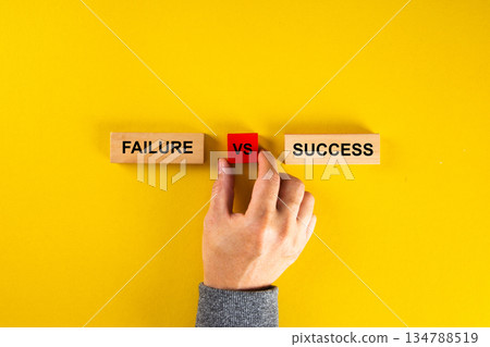 Hand choosing between failure and success on yellow background Hand choosing between failure and success on yellow background 134788519