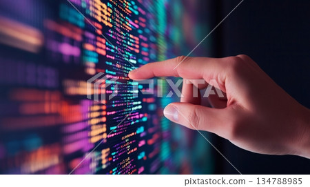 Programmer pointing at vibrant lines of code on a computer screen while working late in the office, focused on developing innovative software solutions and troubleshooting issues 134788985