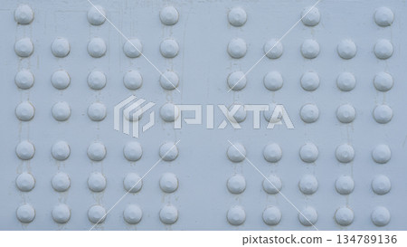 鉚釘和螺栓頭排列在塗漆鋼板上，橋樑背景紋理厚重。 134789136