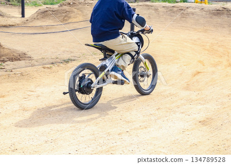 A boy (8 years old) riding an electric mountain bike on a motocross dirt course 134789528