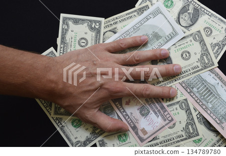 Paper US dollar bills covered by a man's hand Paper US dollar bills covered by a man's hand 134789780
