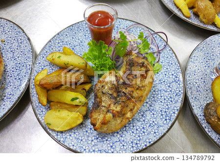 Grilled chicken breast and potato wedges with lettuce and sauce 134789792