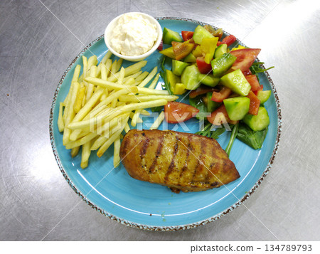 Grilled chicken breast and French fries with a fresh vegetable salad Grilled chicken breast and French fries with a fresh vegetable salad 134789793