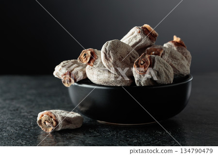 Dried persimmons in a black dish. 134790479