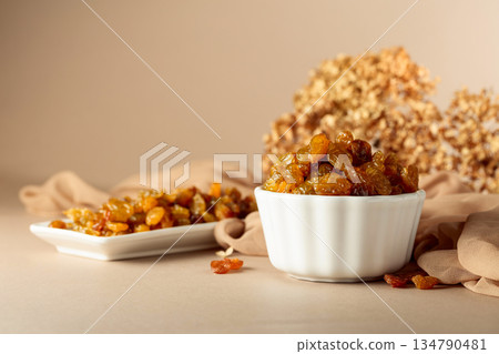 Yellow sultana raisins in a white bowl. 134790481