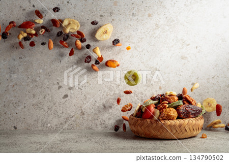 Mix of dried fruits and nuts in motion on a gray background. Mix of dried fruits and nuts in motion on a gray background. 134790502