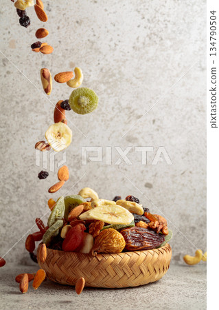 Mix of dried fruits and nuts in motion on a gray background. Mix of dried fruits and nuts in motion on a gray background. 134790504