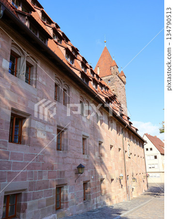 Historic Stone Building With Red Tile Roof And Tower Along Cobblestone Street in Nuremberg Historic Stone Building With Red Tile Roof And Tower Along Cobblestone Street in Nuremberg 134790513